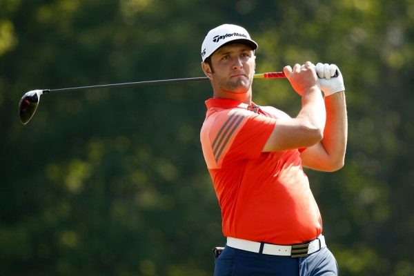 Jon Rahm watches his golf ball after a swing