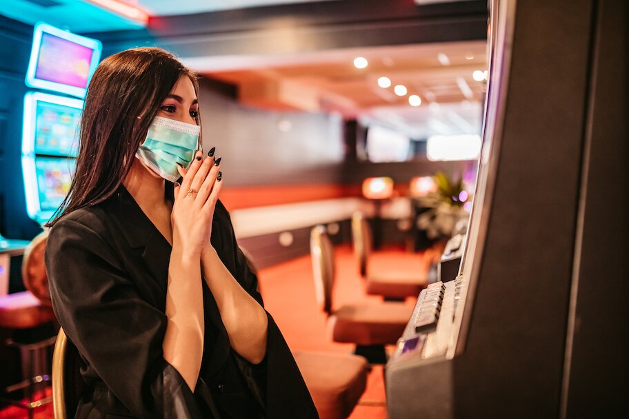 woman plays slot machine wearing n95 mask in casino during covid 19 pandemic