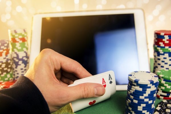 playing cards and poker chip in front of computer