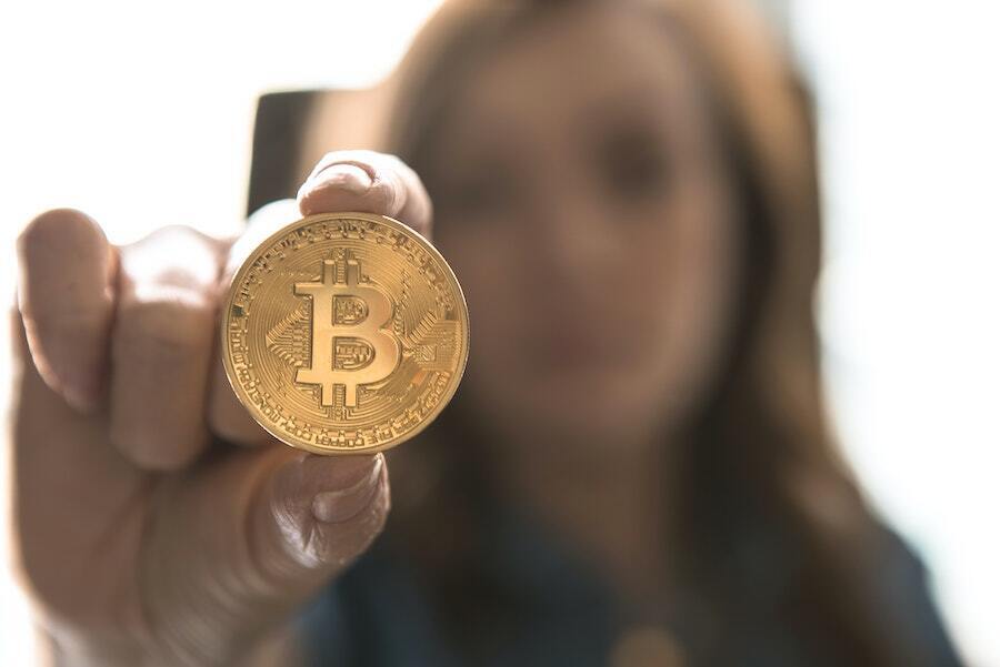 woman holding gold coin representing bitcoin