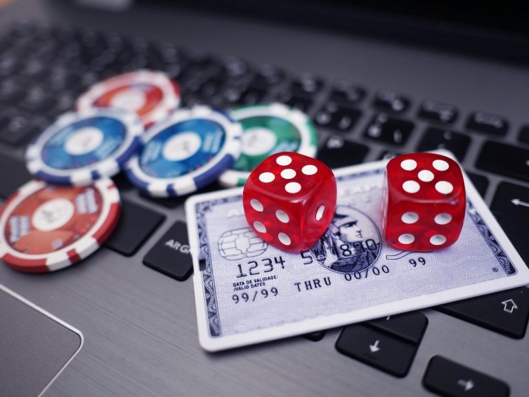 credit card, dice, and poker chips on a laptop to represent online casinos