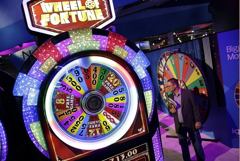 A man stands in front of a Wheel of Fortune game
